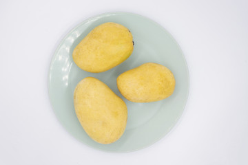 Yellow mango top view on white background. Tropical fruit mango served banner template. Exotic fruit on plate flat lay.