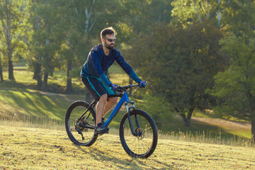 A cyclist rides the hills, Beautiful portrait of a guy on a blue bicycle