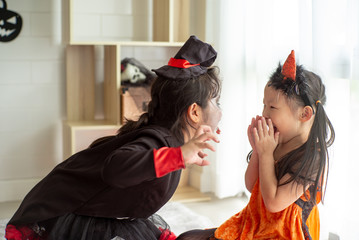 Portrait of two sisters in Halloween costume acting like a ghost frigthening expression to each...