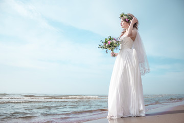 Fototapeta na wymiar Bride on the beach with wedding bouqet soft copy space