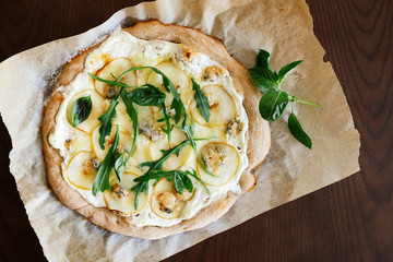 Pizza with cream sauce, pears and cheese dor blue on parchment on wooden table. Flat lay, top view.