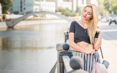 Beautiful young girl in a suit walking around the summer city