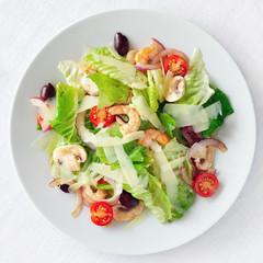 salad with romaine lattuce, prawns, champingons, cherry tomatoes, olives, and red onion dressed with modena vinegar and olive oil and sprinkled with cheese