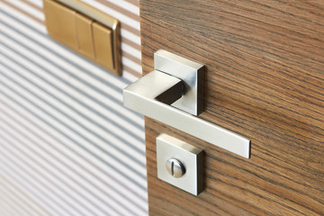Modern metal door handle on wooden door texture