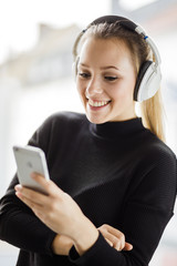 Junge Frau freut sich über die Musik die sie mit ihren Kopfhörer hört