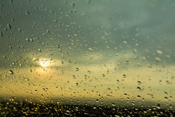 Glass with water drops on out of focus sunset background. Beautiful summer greeting card.