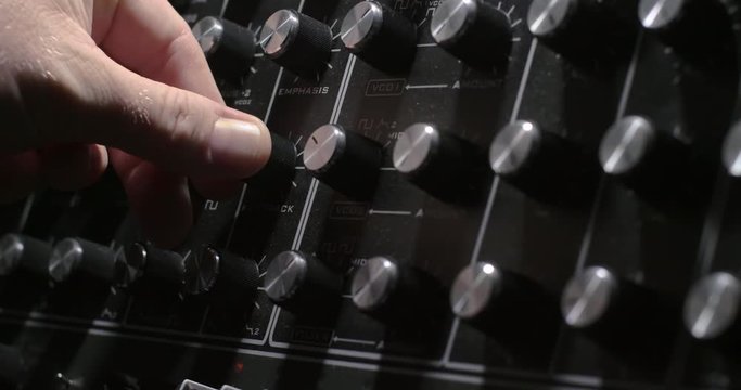 someone turning knobs on a synthesizer