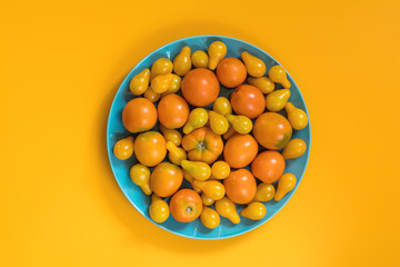Many different yellow  tomatoes on yellow surface.