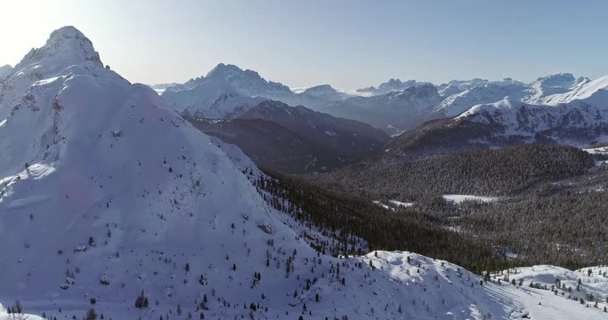 Forward aerial to snowy alpine valley with woods forest at Valparola pass.Sunny sunset or sunrise,clear sky.Winter Dolomites Italian Alps mountains outdoor nature establisher.4k drone flight