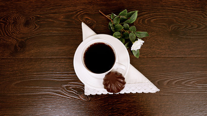 Белая чашка кофе с зефиром и розой на коричневом фоне
