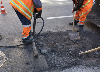 The workers' brigade clears a part of the asphalt with shovels in road construction