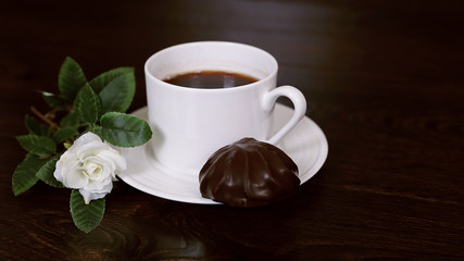 Белая чашка кофе с зефиром и розой на коричневом фоне