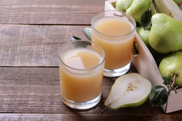 Pear juice in a glass with fresh ripe pears on a brown wooden table