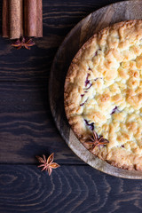 Homemade tasty shortcrust pie with fruit or jam, crumble and spices (cinnamon, anise) on old wooden table background. 