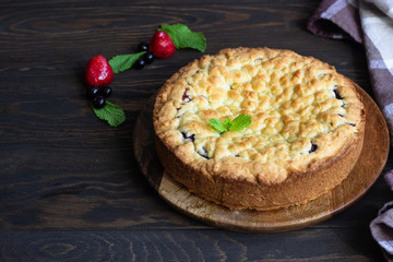Homemade shortcrust fruit or jam pie with crumble and fresh berries with mint on old wooden table background. Homemade pastry with fruit or berry (cherry, plum, strawberry, raspberry) jam.