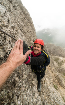 young attractive female mountain climber in the Dolomites of italy giving her guide a high five for success