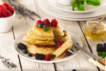 Pancakes with forest fruits berries on white table.