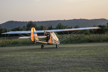 A multicolored light-engine aircraft with a propeller from behind is prepared for take-off at a...