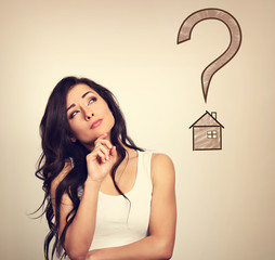 Beautiful serious thinking woman looking up on illustration house and big question and asking....