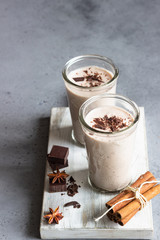 Delicious chocolate drink (milkshake, cocktail or smoothie) in glasses with pieces of chocolate on grey concrete background.
