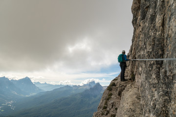 young attractive female mountain climber on a steep and exposed Via Ferrata in Alta Badia in the South Tyrol in the Italian Dolomites