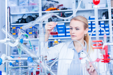 Female laboratory assistant with chemical experiment in scientific laboratory. Female medical or scientific researcher using test tube on laboratory.