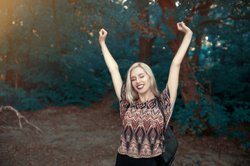 Fototapeta na wymiar Young cheerful woman with hands up in nature