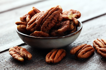 Pecan nuts on a rustic wooden table and pecan nuts in bowl