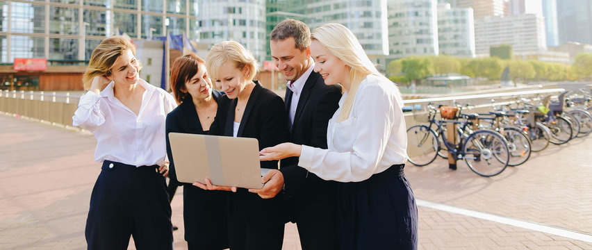 Business Employees Talking With Boss In La Defense Paris Keeping Laptop And Document Cases. Concept Of Successful Management Team Members. Cheerful Biz Partners Resting Outside And Speaking About Good