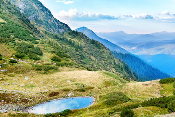 Fototapeta na wymiar Blue lake in the mountains with green grass