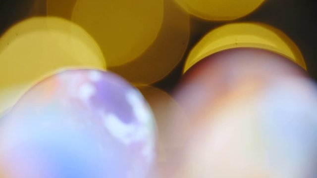 Slide over colorful planets shaped marbles macro shot 4K. Long shot dolly zoom-out with refocusing over colorful marbles and stopping at the single one.