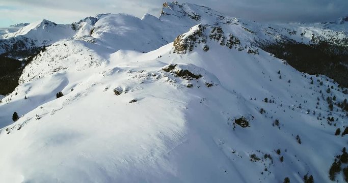 Forward aerial to snowy mount peaks at Valparola pass tilting up.Sunny sunset or sunrise, cloudy sky.Winter Dolomites Italian Alps mountains outdoor nature establisher.4k drone flight
