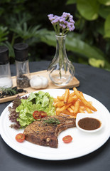 pork chop steak with vegetable salad and potato chips on white plate in the garden. top view.