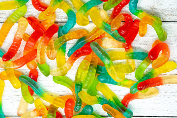 Pile of colorful gummy worms on a wooden background