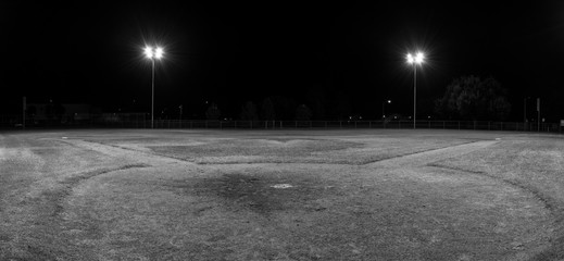 Panorama of empty baseball field at night from behind home pate