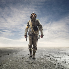 Brave soldier with gas mask walking in a post atomic landscape