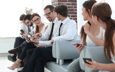 group of young people with gadgets sitting in the office reception