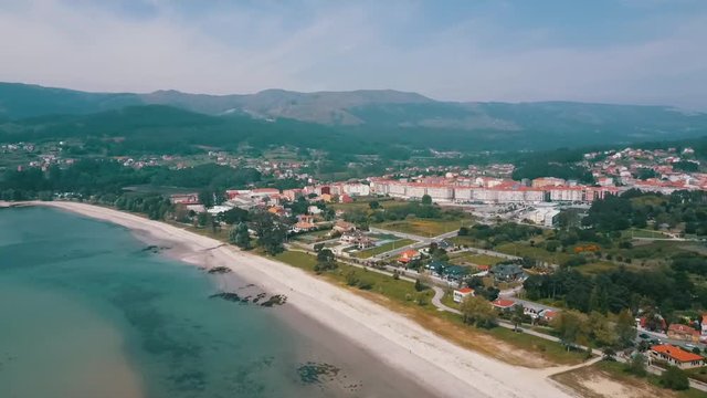 Aerial view of the neighborhood at Boiro bay. In this clip you can see the rooftops of diverse buildings and a panoramic of the beach at this beautiful location in Galicia, Spain.