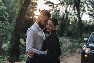 Obraz premium A young married couple came to the lake on a black car during sunset
