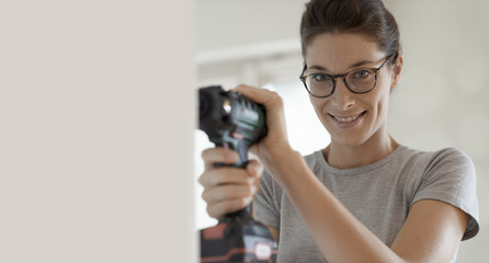 Woman using a drill and working in her new house