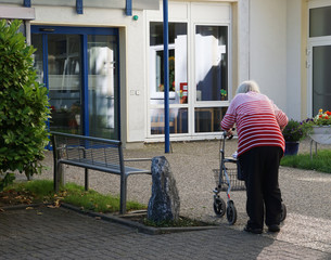 Alte Dame schiebt ihren Rollator zum Altersheim