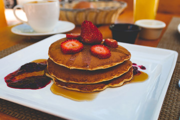 Delicious breakfast pancakes with syrup strawberries and coffee 