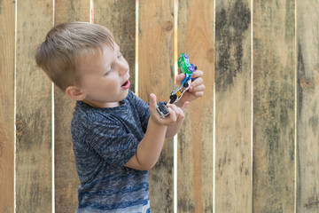 A little boy is holding toy cars.