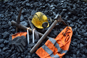Candle with the miner belongings (helmet, gloves, pickaxe, vest, belt) - obrazy, fototapety, plakaty