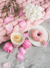 Obraz na płótnie Canvas Cup with cappuccino, doughnut, pink pastel giant blanket, flowers, bedroom, morning concept