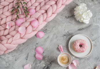 Cup with cappuccino, doughnut, pink pastel giant blanket, flowers, bedroom, morning concept