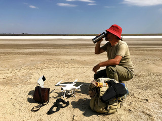 A traveler with a backpack and a drone near a salt lake.