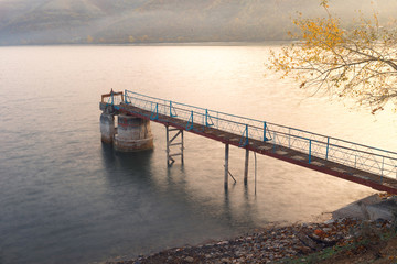 Old iron raft on the lake. Autumn dawn.