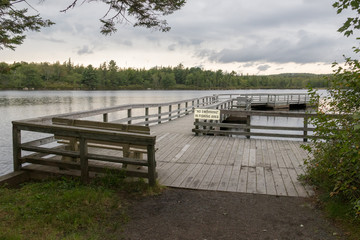 Fototapeta na wymiar Wooden boardwalk lakeside, overcast sky, lewis lake, nova scotia, canada