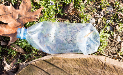 Shredded plastic mineral water bottles and bottle caps on the grass in the park, the concept of environmental protection, environmental protection clogging